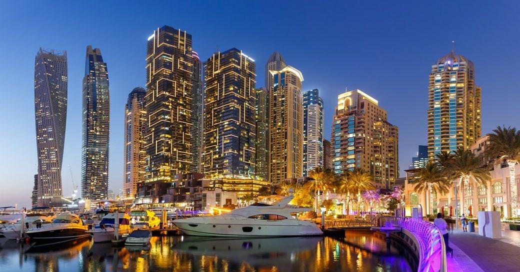 Dubai skyline at night with motor yachts berthed