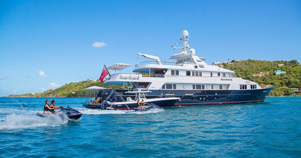 motor yacht Broadwater anchors on a yacht charter as tender and jet skis take to the waters