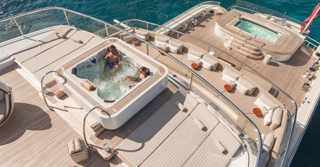 guests relax in the sundeck spa pool with aft section of decks below on show on board superyacht NAUTILUS 