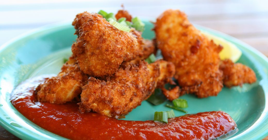 a plate of conch fritters served with a red dressing on a Virgin Islands yacht charter