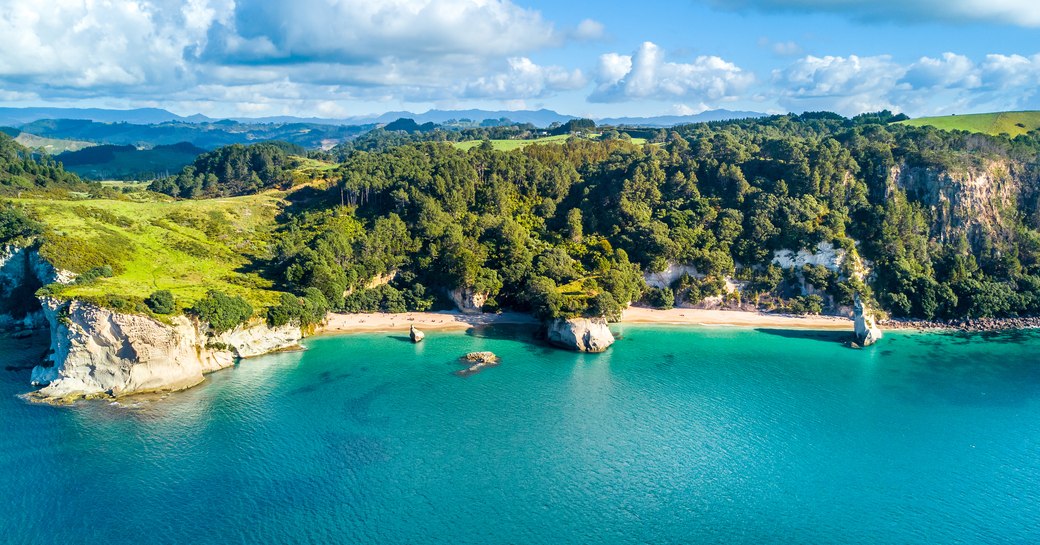 Aerial view on a remote ocean coast with small coves and mountains on the background. Coromandel, New Zealand.
