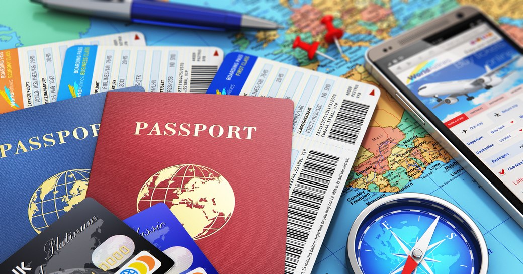 Image of generic travel documents, compass, iphone and pen laid upon a map of the world