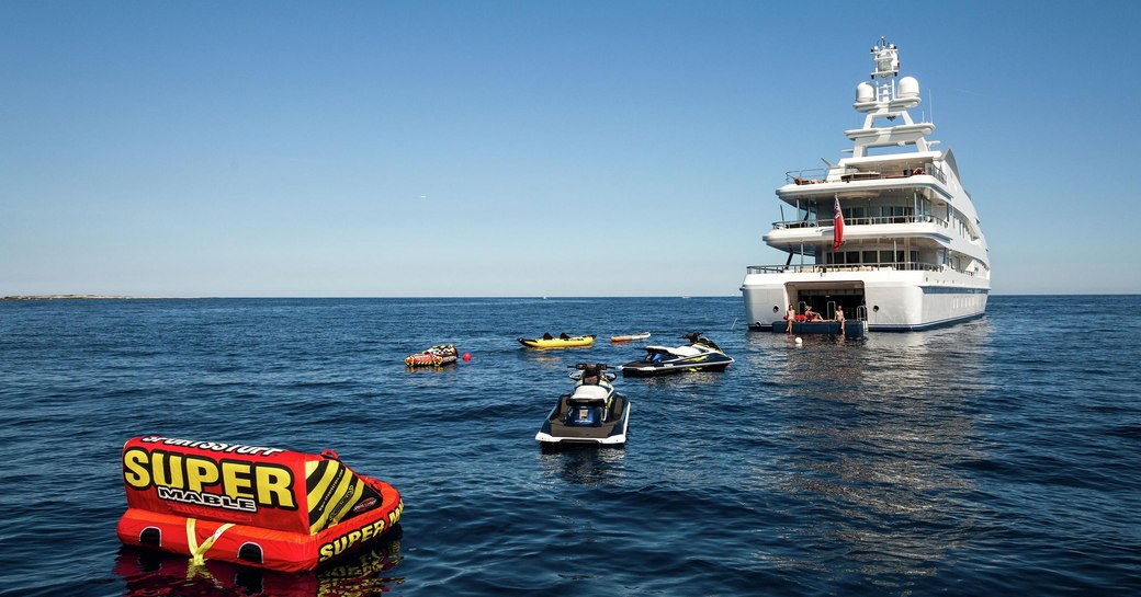 charter guests on the drop-down swim platform of motor yacht Lucky Lady as water toys are spread out across the waters 