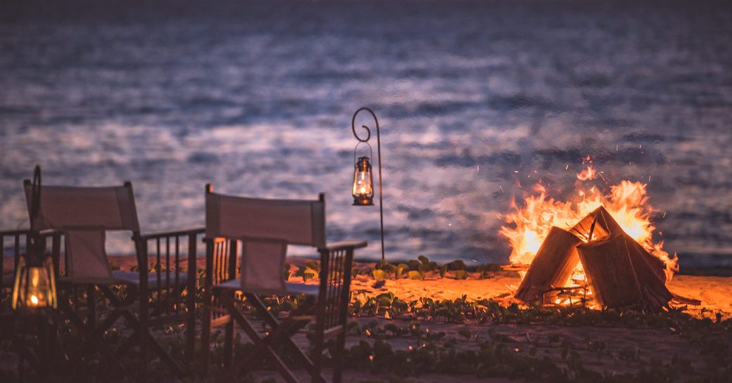 Some chairs around a fire on a beach at sunset on Thanda Island, Indian Ocean