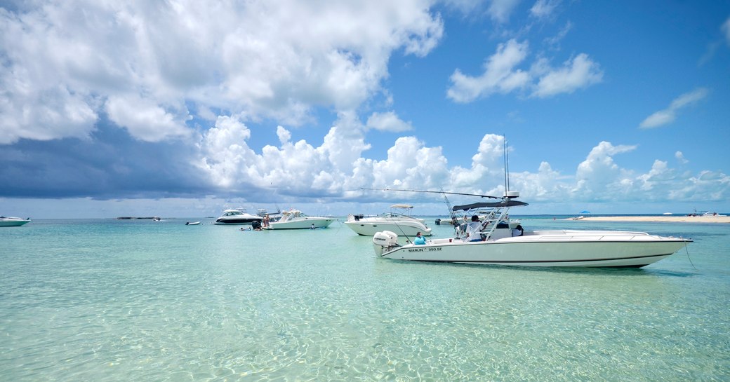 Several boats anchored off Gun Cay in shallow tropical waters in Bimini, Bahamas