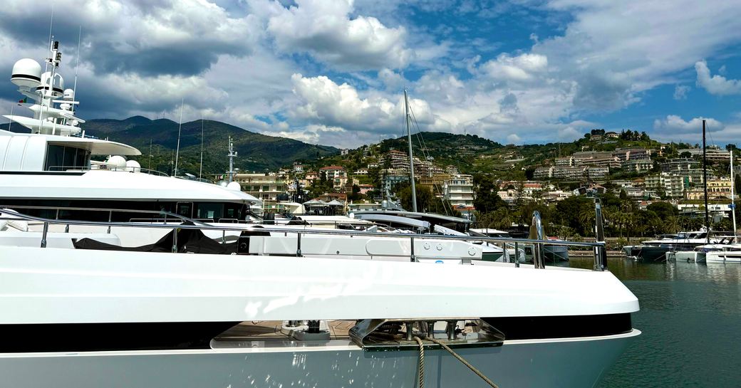 Superyacht charter berthed in marina with elevated terrain in background