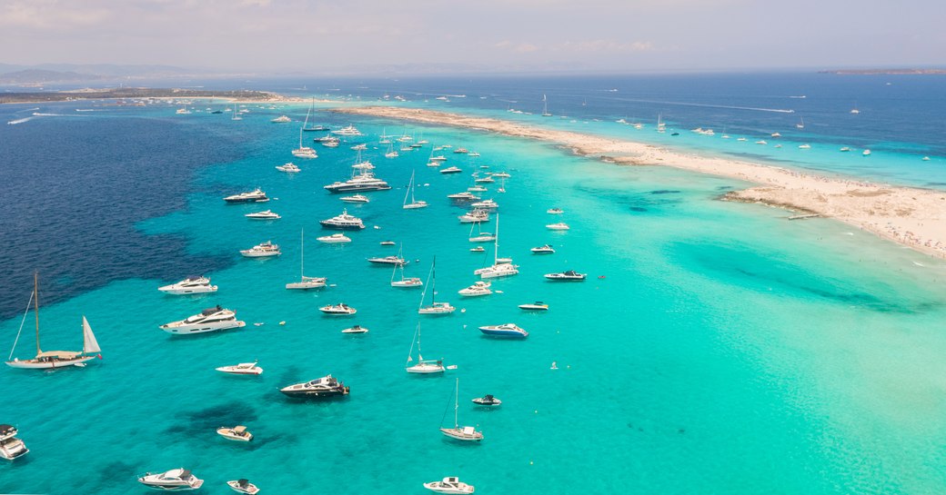 Turquoise waters of Formentera's Espalmador Beach dotted with yachts