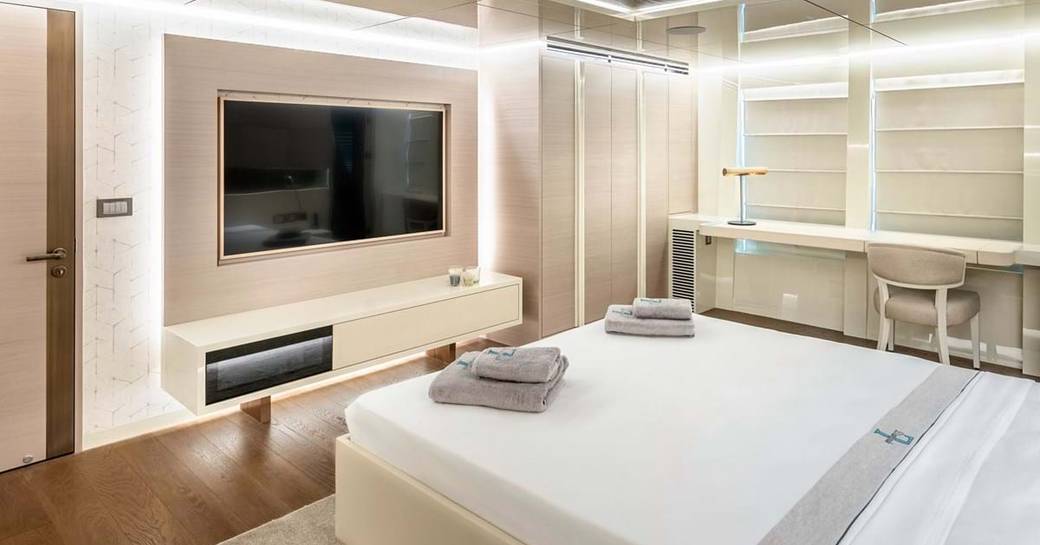 Lightly colored cabin on explorer yacht 'Seven Diamonds' with bed facing flat screen TV