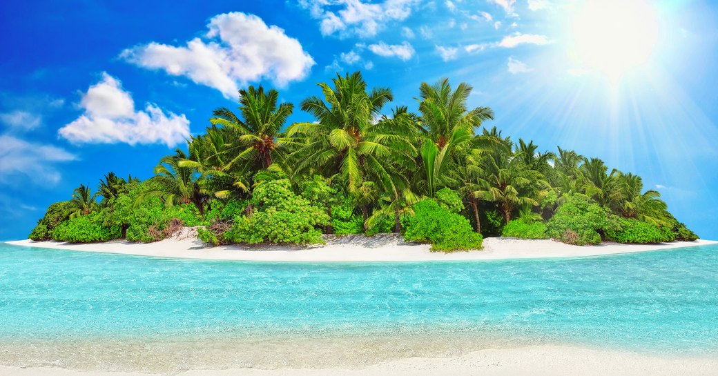 Whole tropical island within atoll in Indian Ocean. Uninhabited and wild subtropical isle with palm trees. Blank sand on a tropical island.