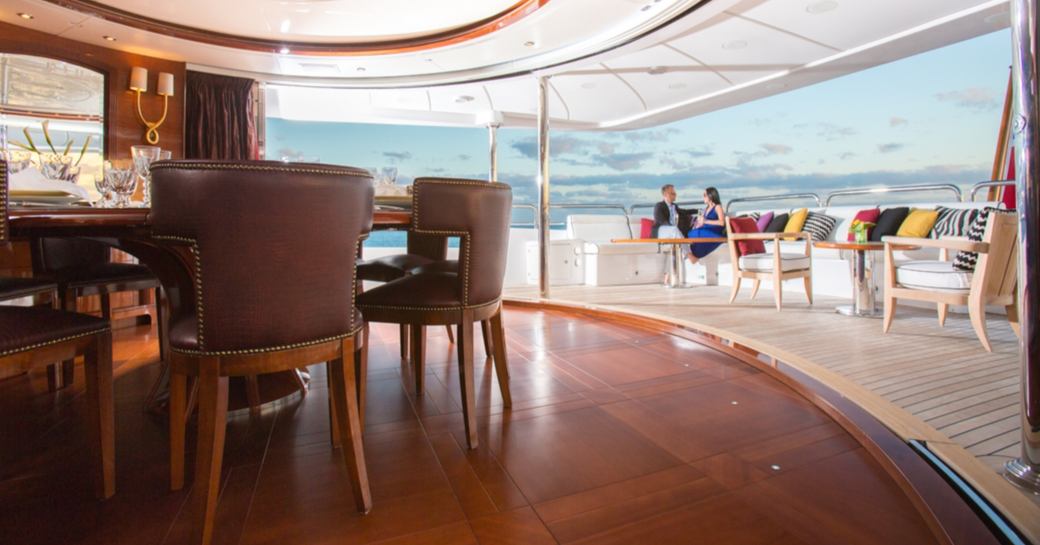 circular dining area with glass panels removed and aft seating area on the upper deck of luxury yacht CHECKMATE 