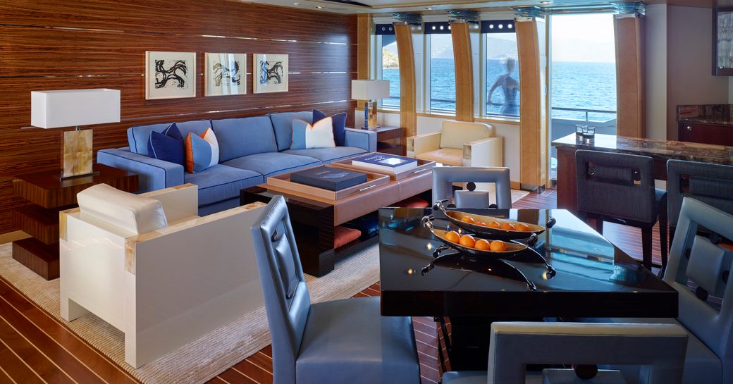 Bright main salon on Victoria Del Mar, with colorful sofas and wooden panelled floor and walls, and doors onto deckside patio