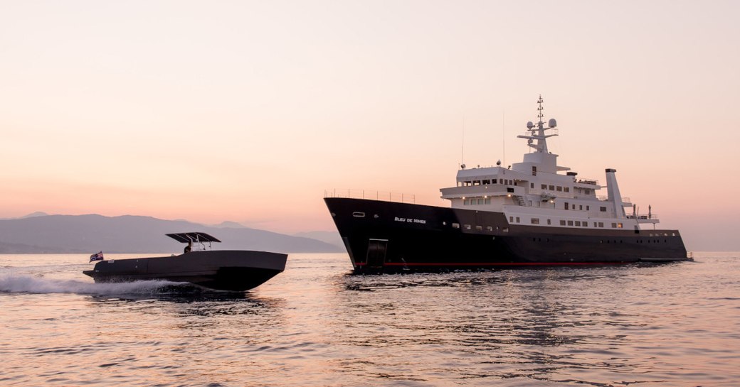 Superyacht 'Bleu De Nimes' on sea with tender boat moving fast in front of it