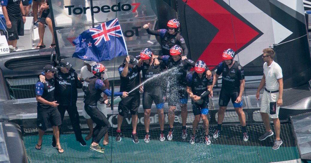 Emirates Team New Zealand celebrate on board foiling catamaran after racing to victory in the 35th America's Cup