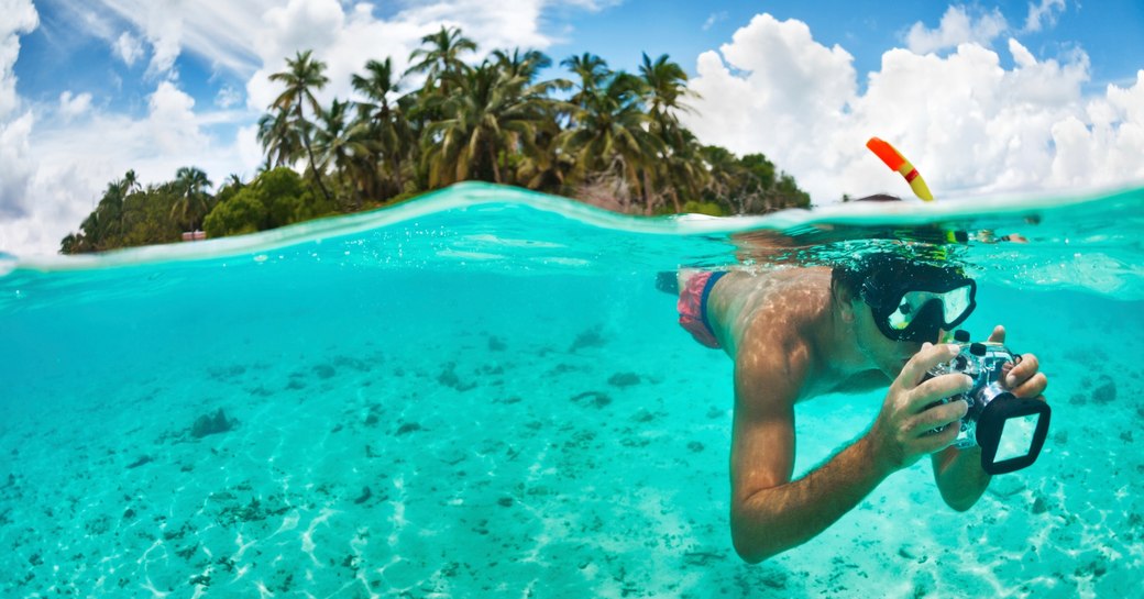 A snorkeler takes photos while swimming in the beautiful waters of the Maldives