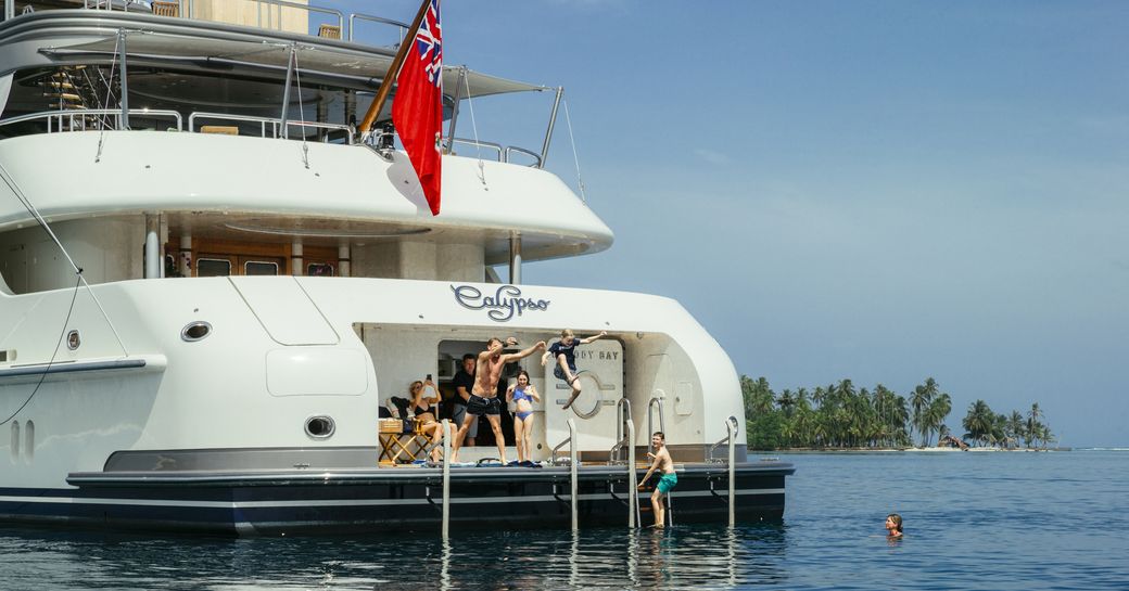 family and children jumping off the beach club of superyacht calypso