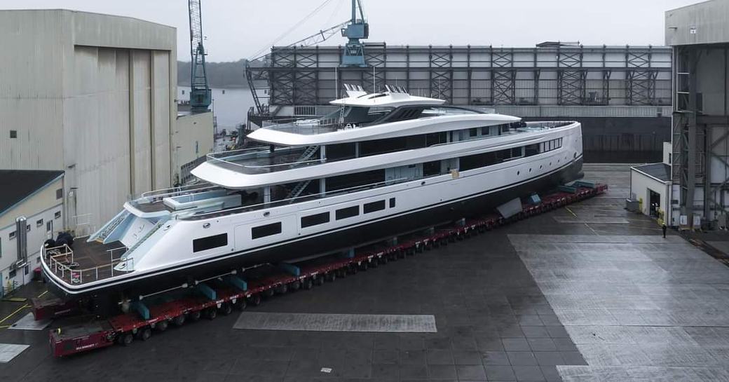 Superyacht CALI being transported from construction shed, surrounded by Lurssen facility buildings