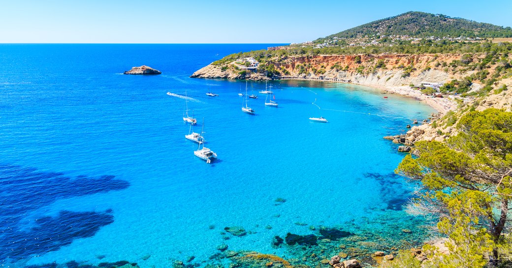 Bateaux à voile sur la baie de Cala d'Hort avec une belle eau de mer bleu azur, île d'Ibiza, Espagne