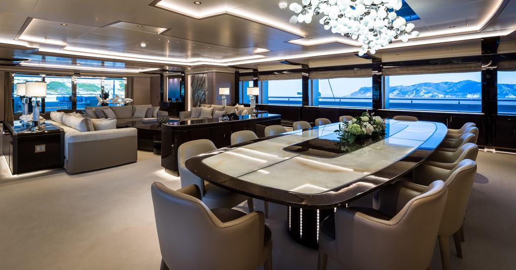 Open plan interiors on superyacht O'PARI with dining table and comfortable chairs and large windows