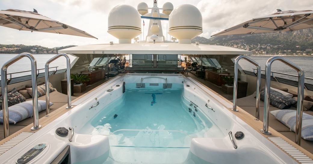 Swimming pool with sunloungers and canopies onboard charter yacht ARBEMA