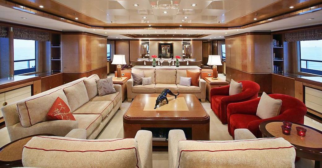 deep sofas in cream fabrics and red arm chairs form a seating area in the main salon of charter yacht JAGUAR 