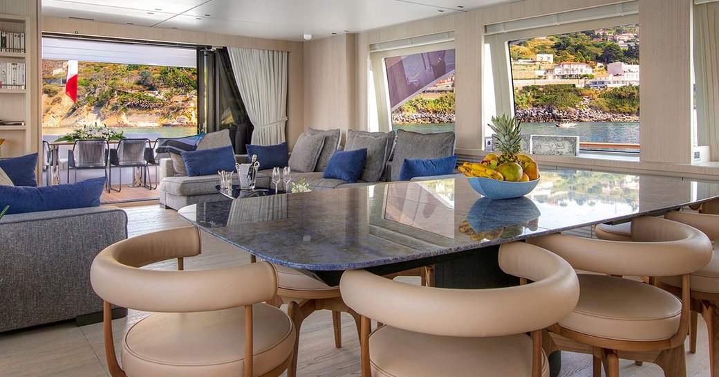 Interior of luxury yacht ARSANA with table in foreground and comfortable seating in background