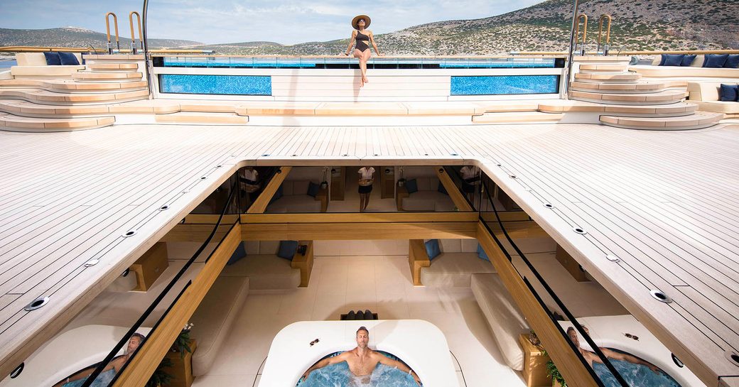 the main aft deck and beach club of superyacht FLYING FOX by lurssen which features a large glass encased pool and boasts a retractable deck that opens yup to the jacuzzi in the beach club