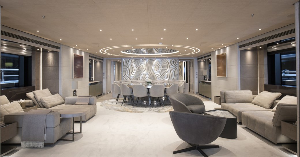 Lightly colored living area on superyacht SEVERIN'S with number of comfortable chairs and sofa, and circular dining table at far end
