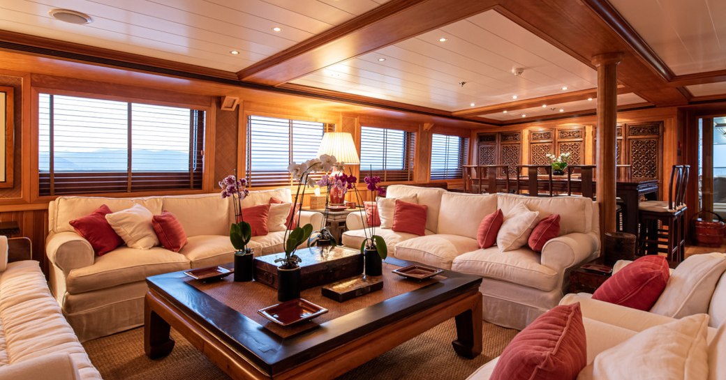 Ornate social area on superyacht 'Bleu De Nimes' with cream sofas and wooden detailing