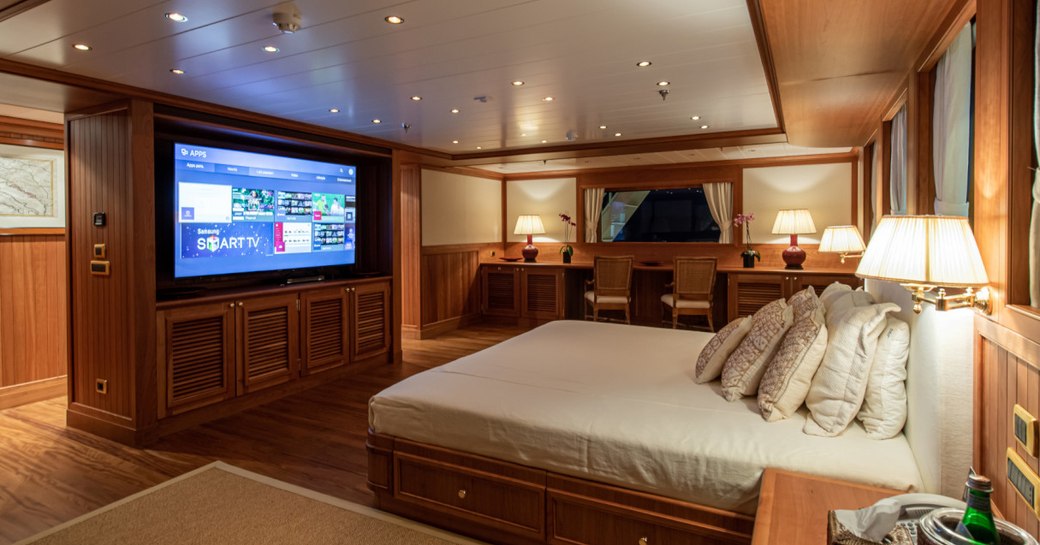 Large master suite on superyacht 'Bleu De Nimes' with bed facing flat screen TV in wooden detailed room