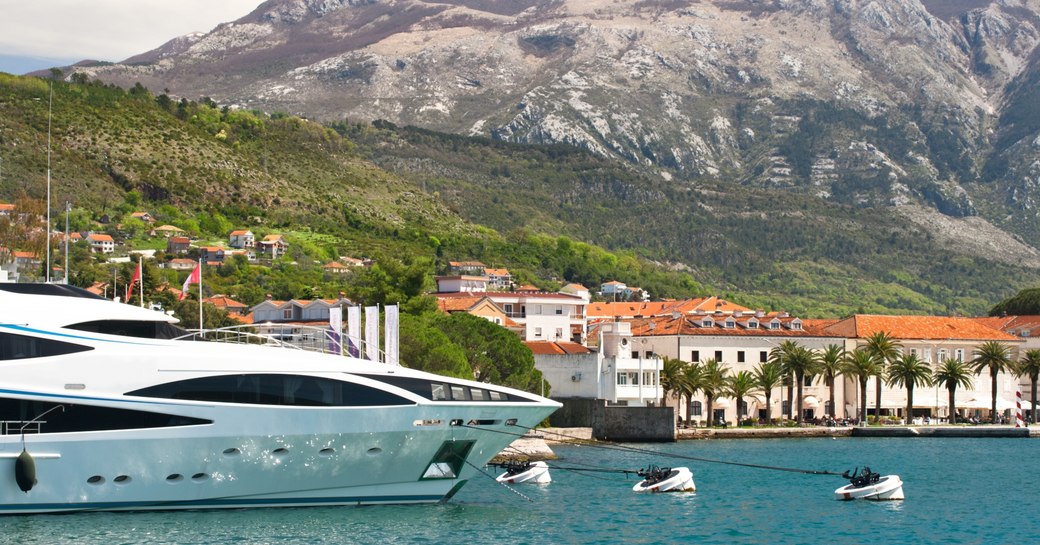 superyacht lines up in yacht club in Montenegro looked over by dramatic mountain range