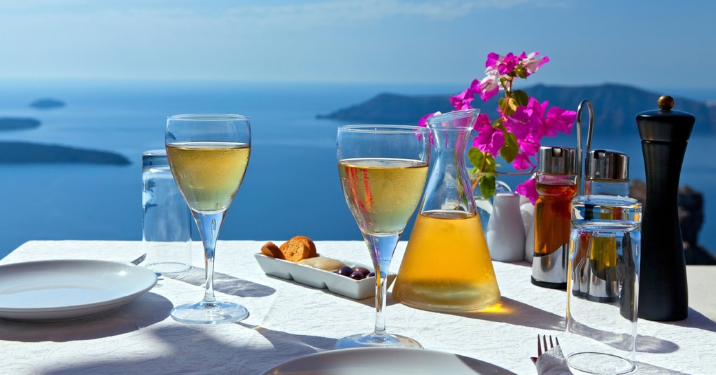 table set with local wine in Oia with stunning views of the Santorini coast in Greece