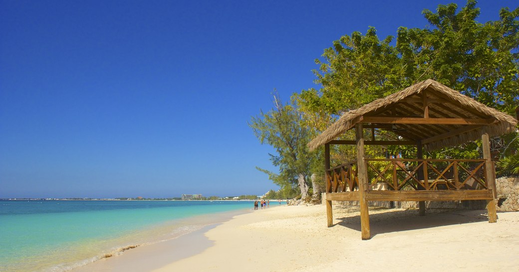 Wooden hut stood on white sandy beach in the Caribbean overlooking the sea and blue sky. 