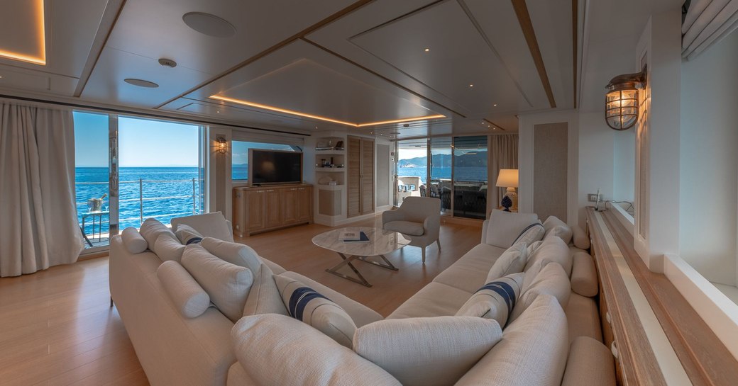 Comfortable L shaped sofa in front of TV with open balcony doors on Motor yacht 'My Way'