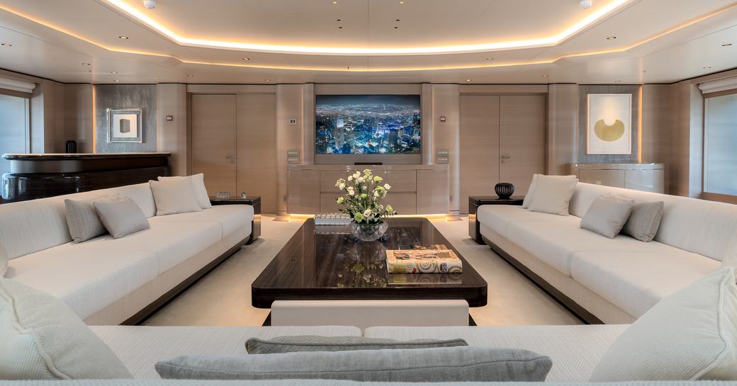 Lightly colored sofas surround wooden dining table on superyacht O'PARI