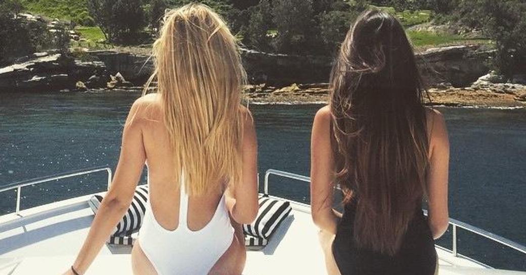 Two girls soak up the rays in swim suits on the bow of a yacht in Sydney