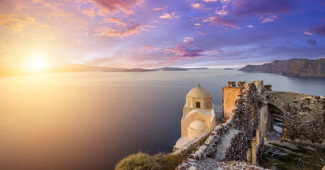 shot of the sun setting from Oia in Santorini with views across the caldera