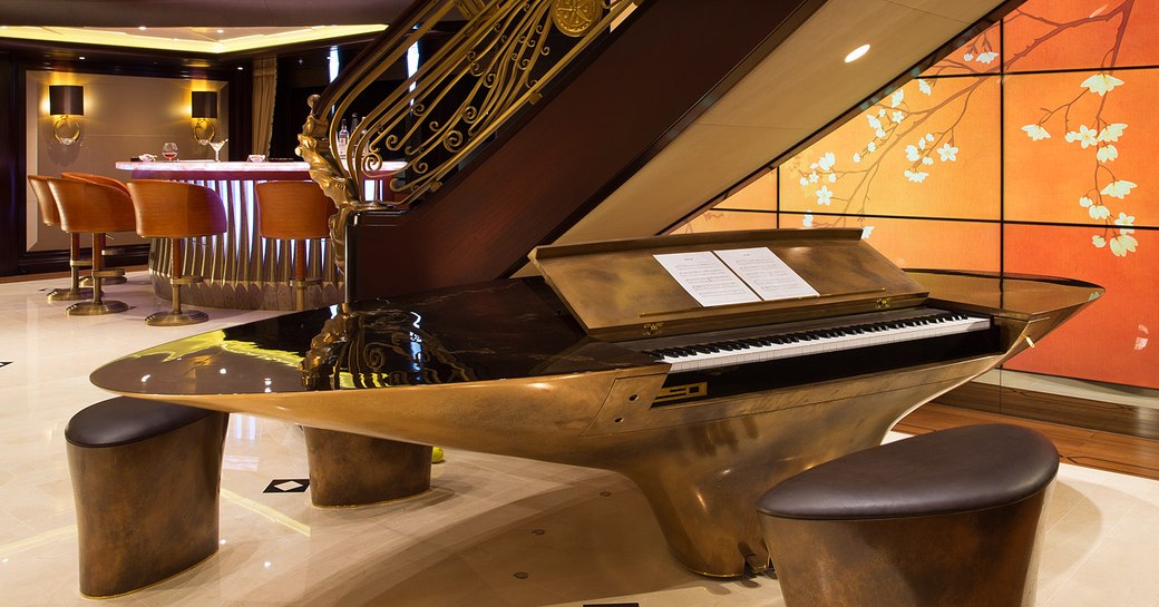 piano built into a bar with video walls and staircase behind on board superyacht KISMET 