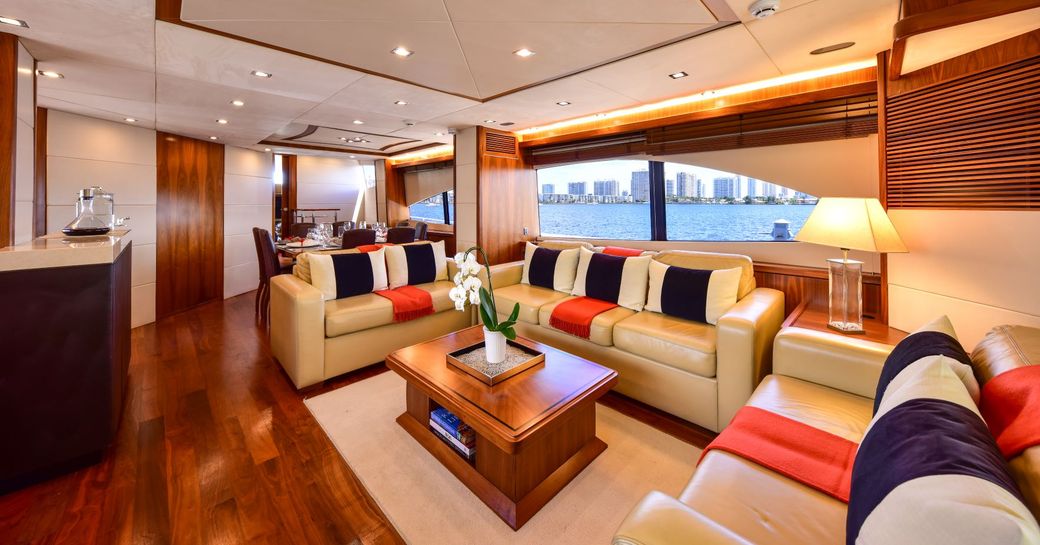 Interior lounge area onboard charter yacht CATALANA, three sofas arranged in a U shape with large windows behind.
