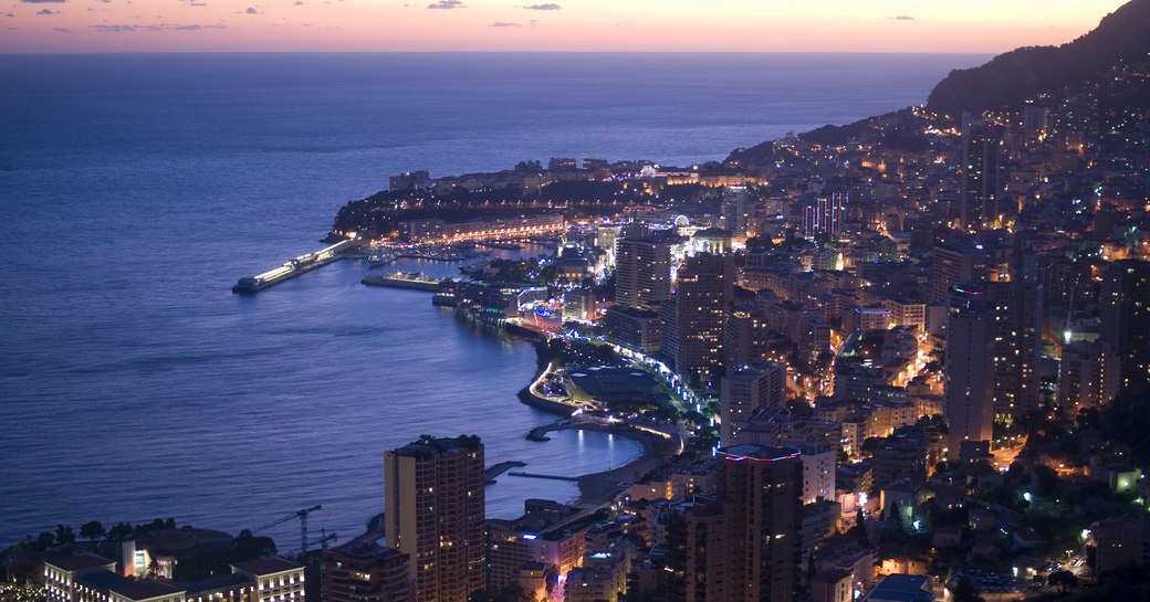 View across Monaco coastline at night with many buildings lights visible