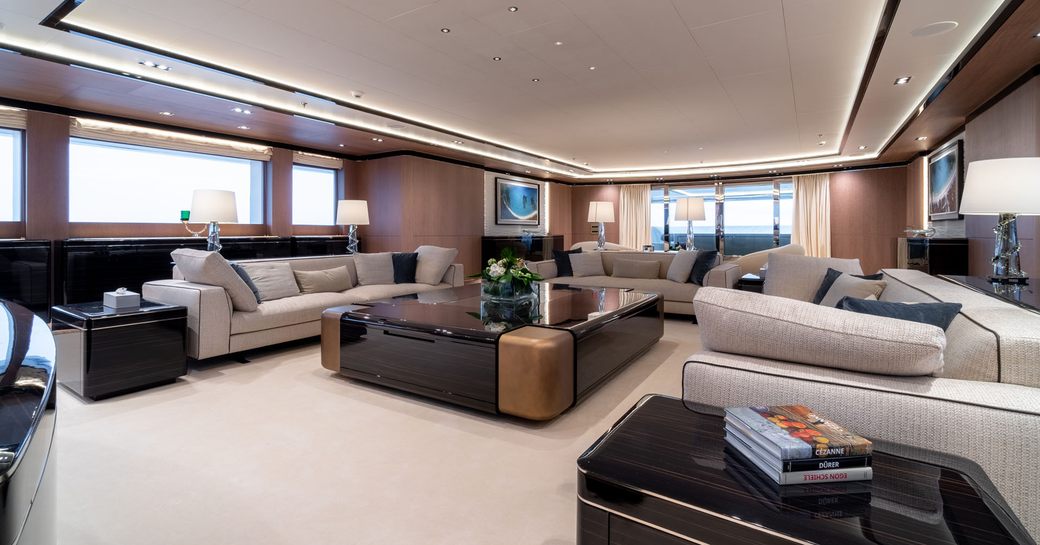 large cream sofas surround a wooden coffee table in the main salon aboard superyacht O’PTASIA 
