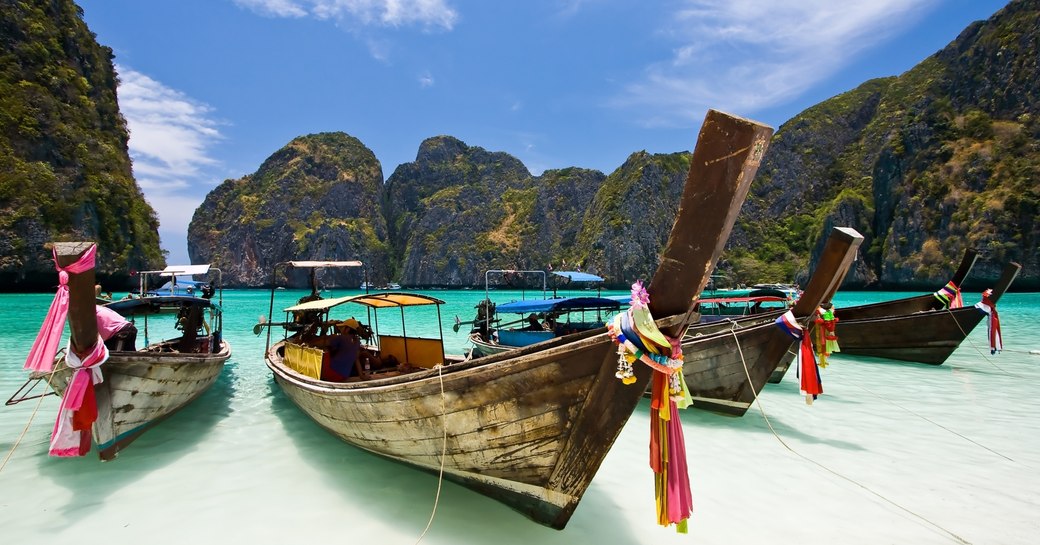 traditional fishing boats on the shore of a white-sand beach in Phuket