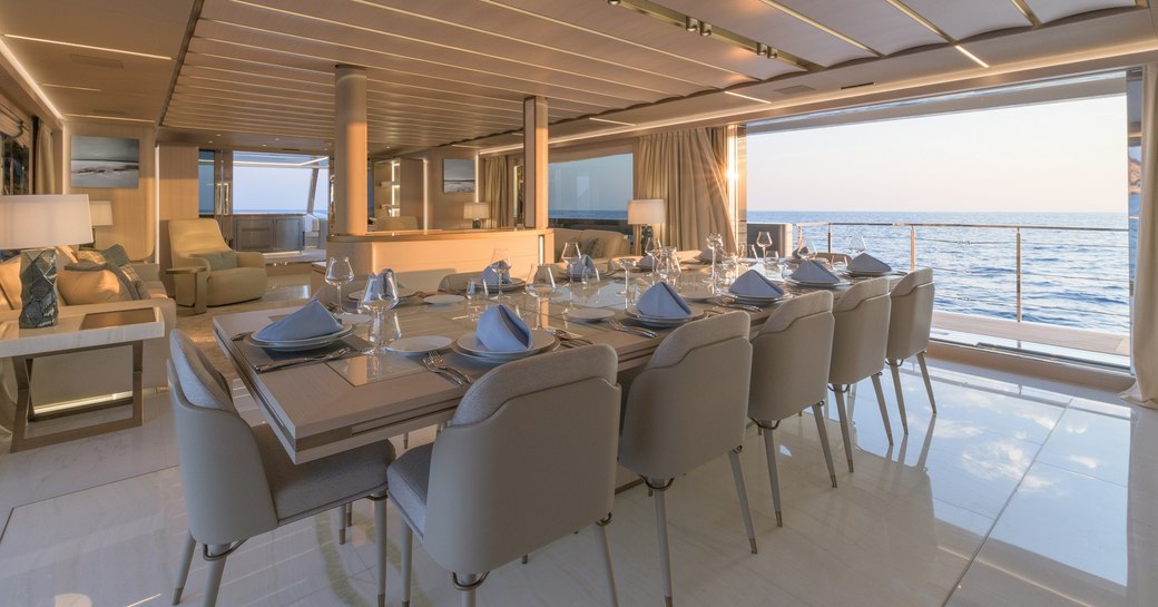 Formal dining table laid out with balcony open and view to sea on superyacht EIV