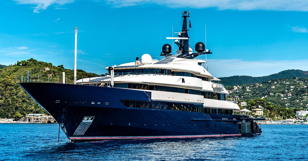 A motor yacht with a blue hull sits at anchor