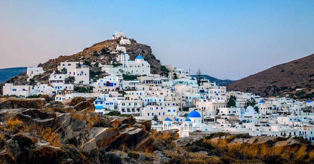 white cubed building with blue-doomed churches tumble down the hillside in Oia, Santorini, Greece