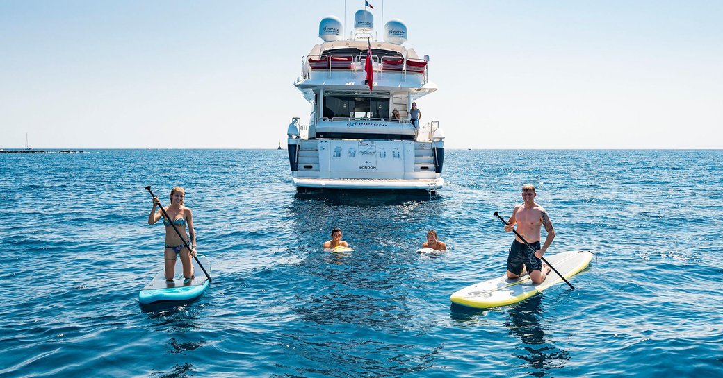 charter guests try out the paddle boards as luxury yacht ‘Excelerate Z’ anchors nearby