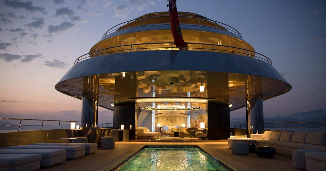 Outdoor area on superyacht SAVANNAH lit up at night with pool visible