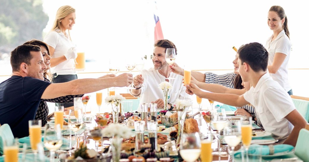 A charter group cheers at a dining table on a yacht