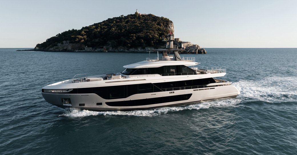 Charter yacht LUZ DE MAR underway, surrounded by sea and a small island in the background