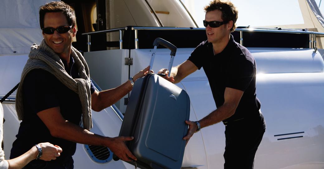 A deck crew member passes a guest luggage aboard the yacht