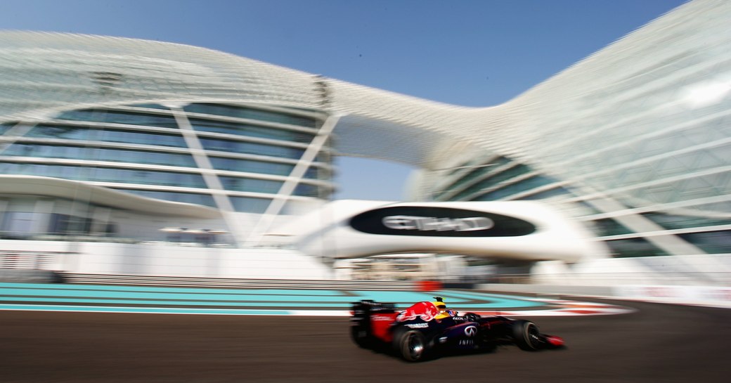 Car in focus as it goes under Etihad signage with arches of Yas Viceroy Hotel above during Abu Dhabi Grand Prix